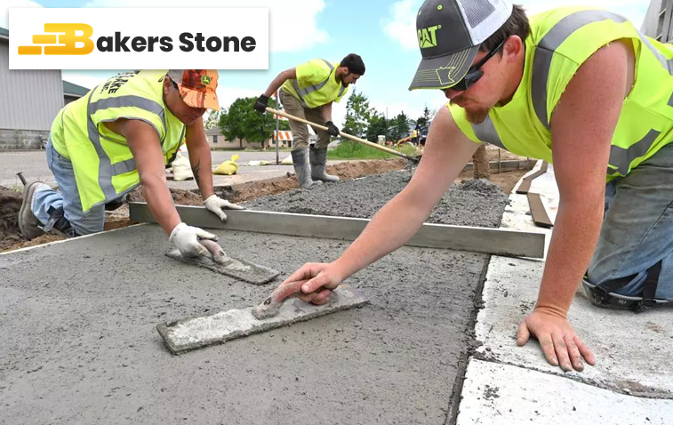 Workers smoothing and shaping a concrete driveway by hand with tools.